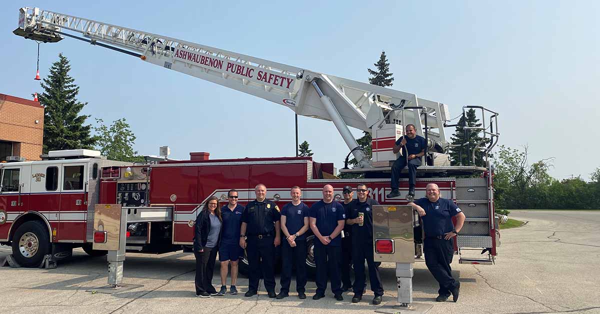 Emergency responders pose with a ladder truck.