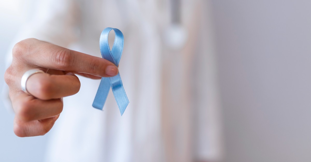 Doctor holding a light blue ribbon representing National Prostate Cancer Awareness Month.