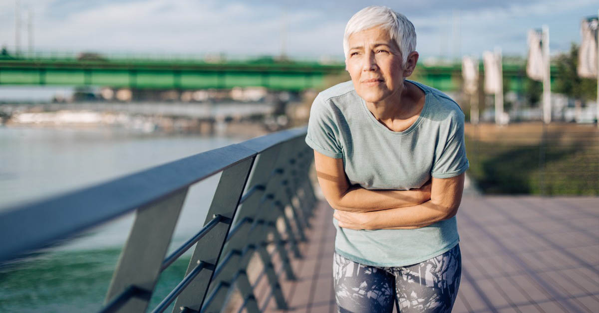 Older woman experiencing discomfort above the waist, which could be a symptom of heart disease.