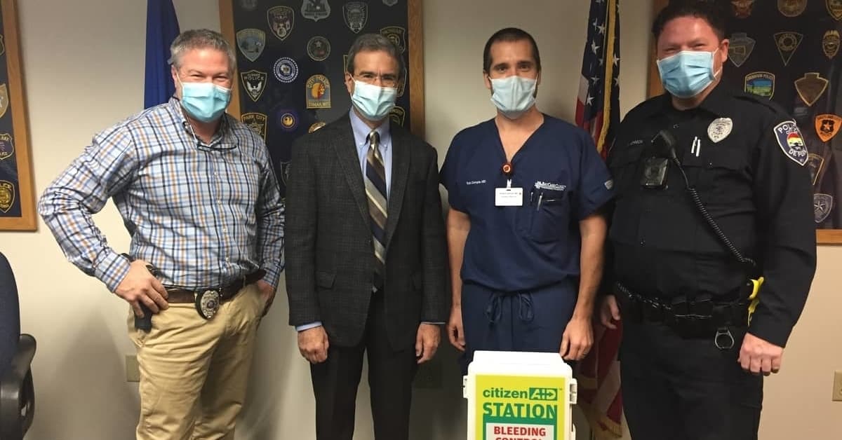 BayCare Clinic representatives pose with De Pere Police officers showcasing Stop the Bleed kits