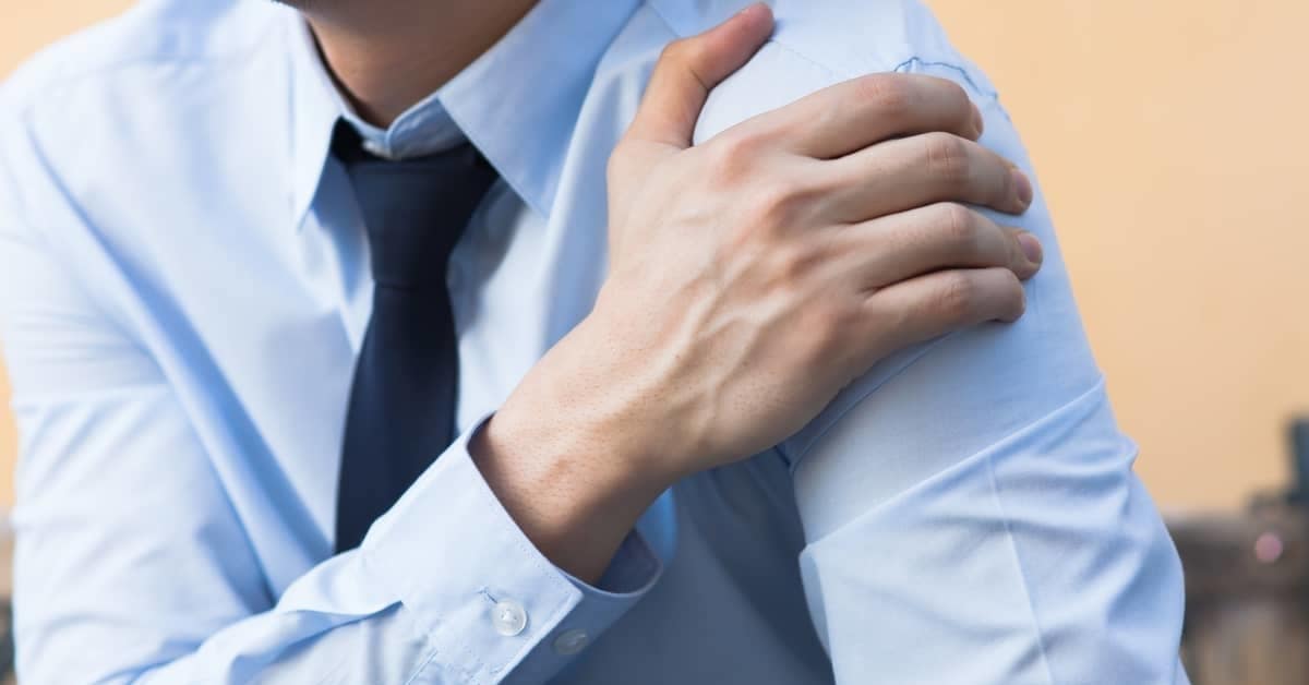 Man holding shoulder as if in pain